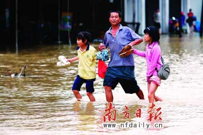 樂昌市政府前和街道被水浸,一位家長(zhǎng)帶著孩子涉水而行?！　」攘⑤x童銅韶朱裕超攝