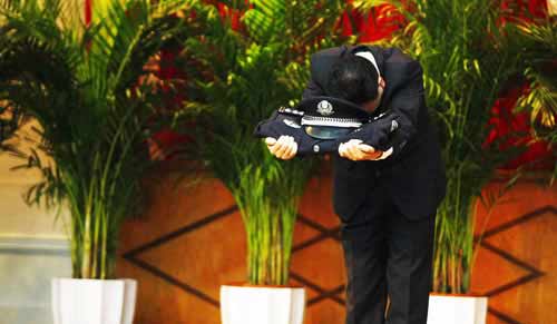 原市局刑警總隊(duì)二支隊(duì)副支隊(duì)長鄭某手托警服警帽向全場(chǎng)鞠躬。圖片來源：重慶晚報(bào)