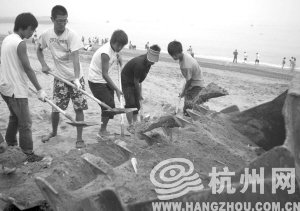大連市金石灘國賓浴場，工作人員將帶有油污的沙子清理掉。