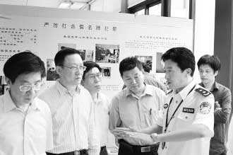 圖為公安部經(jīng)偵局副局長(zhǎng)高峰(右)向公安部特邀監(jiān)督員們介紹“亮劍”行動(dòng)展覽情況。 