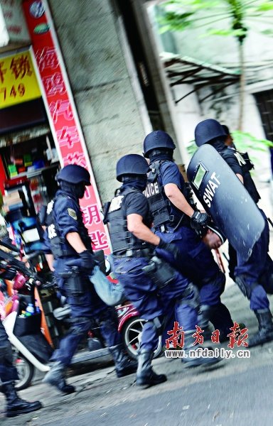 特警將嫌疑人（紅圈內(nèi)）押上警車。