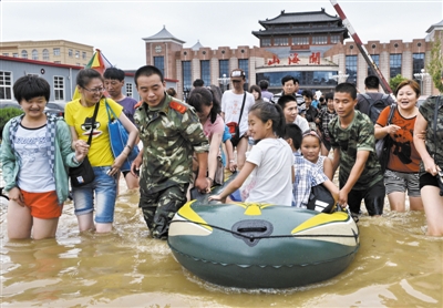 昨日，消防戰(zhàn)士在秦皇島市山海關(guān)火車站涉水運送旅客。當(dāng)日，受持續(xù)強降雨影響，河北省秦皇島市海港區(qū)、山海關(guān)區(qū)等地出現(xiàn)內(nèi)澇，部分列車停運。 新華社發(fā)