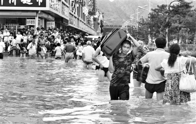昨日，一名消防戰(zhàn)士在秦皇島市山海關(guān)火車站站前廣場涉水幫助旅客運送行李。 新華社發(fā)