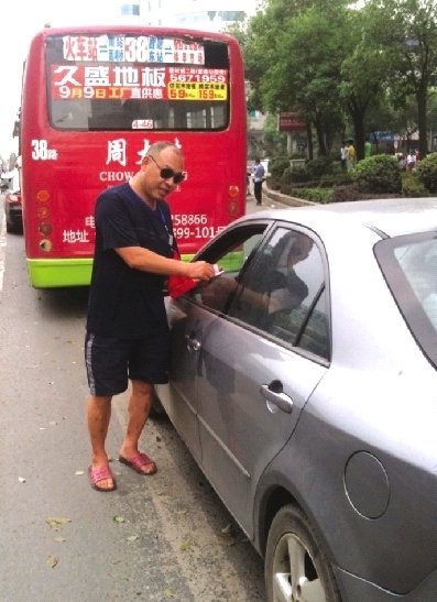 8月17日，邵陽(yáng)市西湖路與寶慶路交接處，穿拖鞋戴墨鏡的市容監(jiān)督員在對(duì)占?jí)喊唏R線停放的車輛罰款。圖/記者龍?jiān)? hspace=