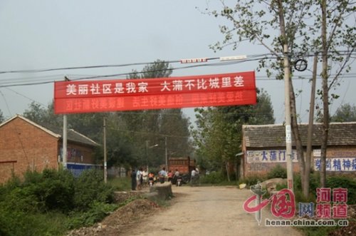 死者的家屬在村口迎接前來吊唁的親友，紅色的橫幅看上去更具諷刺意味。