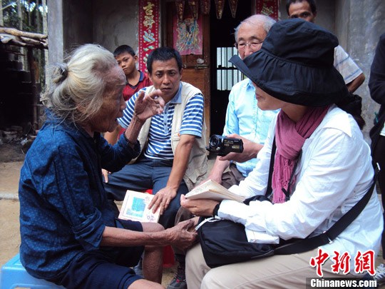 日本“海南島近代史研究會(huì)”創(chuàng)始人佐藤正人第22次到海南島調(diào)查日本侵瓊史。圖為在保亭黎族苗族自治縣南林鄉(xiāng)羅葵村，金靜美握著86歲老人林亞金的手。中新社發(fā) 張茜翼 攝