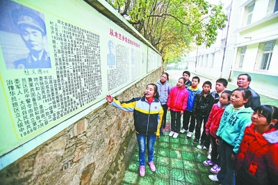 上圖：學校文化墻前，小講解員講述開國將軍杜義德的故事。記者何曉剛 攝