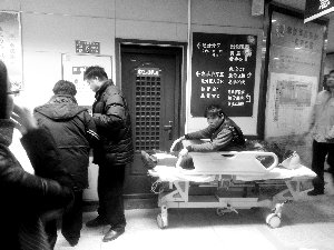 受傷工人小王坐在病床上候診。