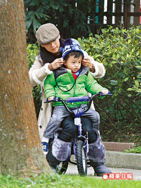 張柏芝抱quintus坐踩單車，又細心幫他整理冷帽