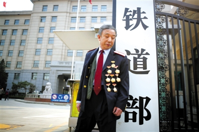 3月14日，鐵道部大門口，一位胸前掛著多枚勛章的鐵道部老職工與鐵道部牌子合影。 新京報(bào)記者 侯少卿 攝