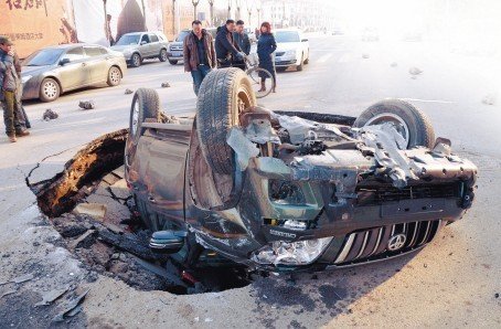沈陽(yáng)一道路現(xiàn)大坑 霸道車遭橫禍四腳朝天(圖)