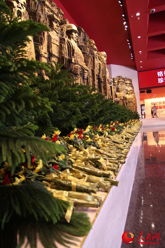 紀(jì)念館門廳的《銅墻鐵壁》雕塑墻，和人們獻(xiàn)上的花。邱越攝